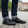 Adulto usando zapatillas Saguaro Wish II negro en entorno urbano.