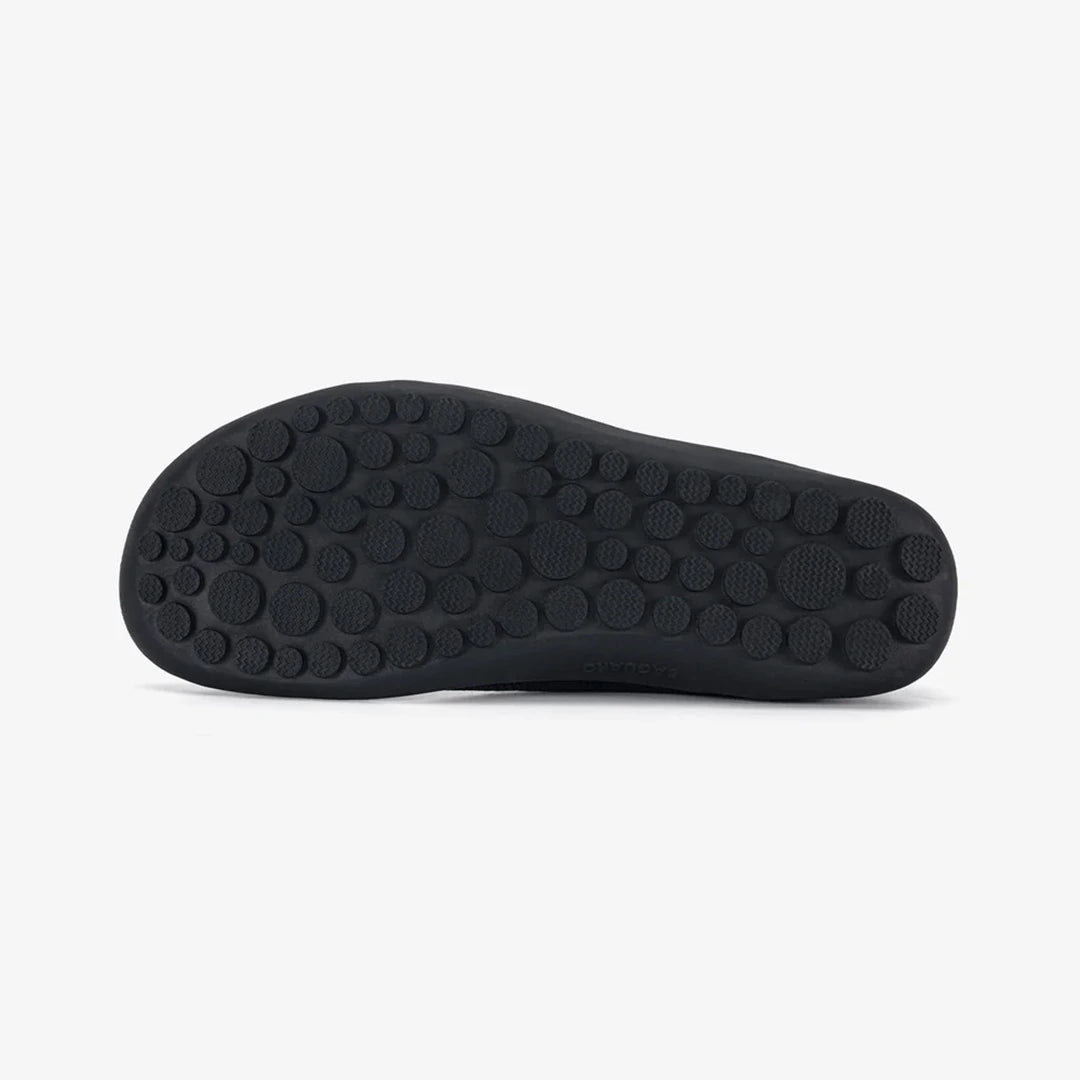 Suela plana negra de una zapatilla barefoot con diseño de burbujas antideslizantes.