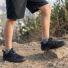 Vista lateral de zapato negro colegial barefoot en uso real sobre pavimento.