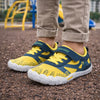 Niño jugando en la arena con zapatillas barefoot amarillas de alta visibilidad y flexibilidad.