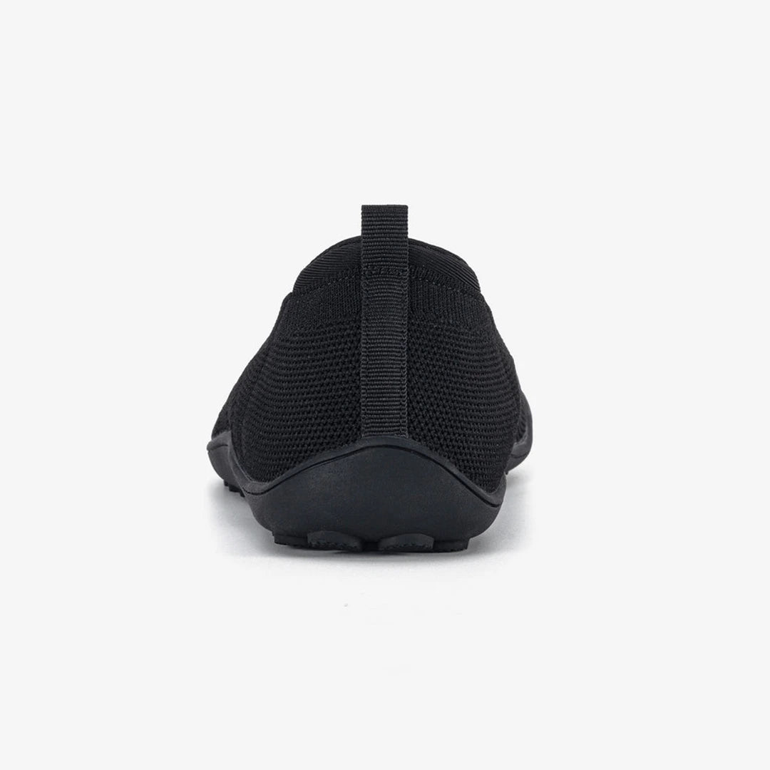 Detalle trasero de un zapato barefoot negro que asegura una pisada estable y zero drop.